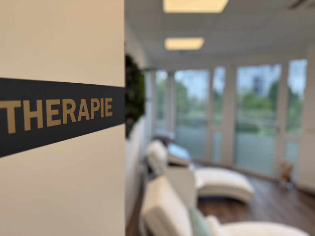 Wandschild mit der Aufschrift Therapie im Praxisflur